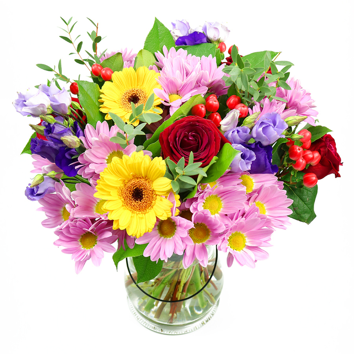 In this image, a generous mixed bouquet overflows from a clear glass vase, its colours intensified by the crisp white background, as if waiting to be delivered to a cosy Bow café near the Regent's Canal. At the centre, rich red roses draw the eye, each bloom layered with soft, velvety petals that curl inward to form classic, romantic spirals. Flanking them, bold yellow gerberas with dark brown-orange centres offer a burst of sunlight, their broad, daisy-like faces full of optimism and cheer. Encircling these focal flowers, clusters of soft pink and pale lavender chrysanthemums create volume and texture, their many fine petals and tiny yellow hearts giving the bouquet a gentle, almost cushiony appearance. Threaded among the daisies and roses are stems of purple and lilac lisianthus, their slender buds and bell-shaped blossoms adding a graceful, contemporary twist, like the refined touches you see in renovated Bow warehouses turned studios. Small, round hypericum berries in vivid red dot the design, lending a playful, bead-like texture that catches the light. A variety of lush green foliage supports and frames the arrangement-broad, glossy leaves provide depth, while lighter, more delicate sprigs soften the edges and introduce a sense of movement. Through the clear vase, you can see the neatly cut stems gathered together in clear water, revealing the underlying structure and care that went into the floristry. The bouquet radiates joyful celebration and warm emotion, ideal for marking milestones in Bow, from a new home off Devons Road to a birthday dinner near Mile End Park, or simply for bringing colour and life into an East London living room.